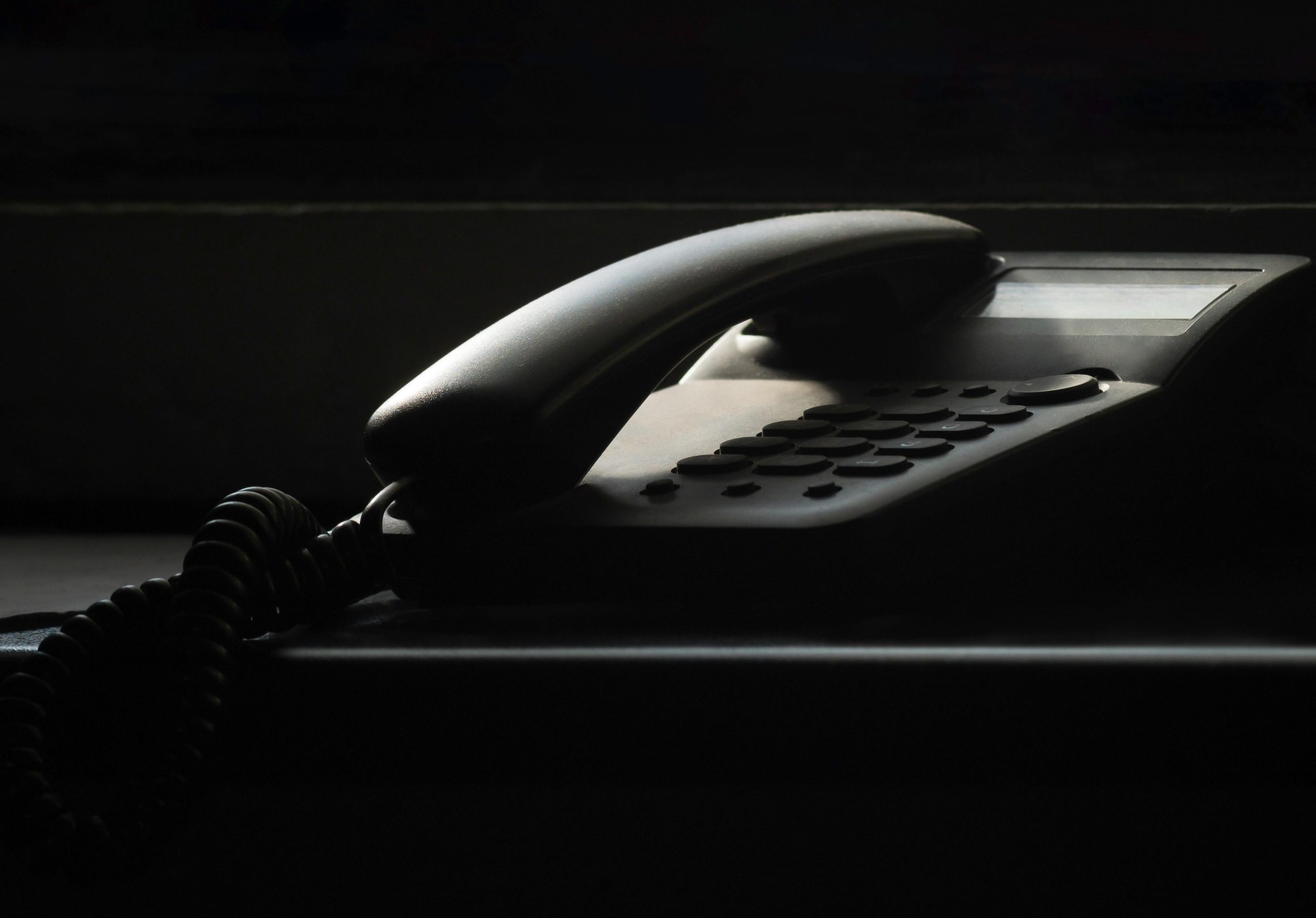 A close-up of a vintage landline phone in dramatic shadow lighting, evoking nostalgia.