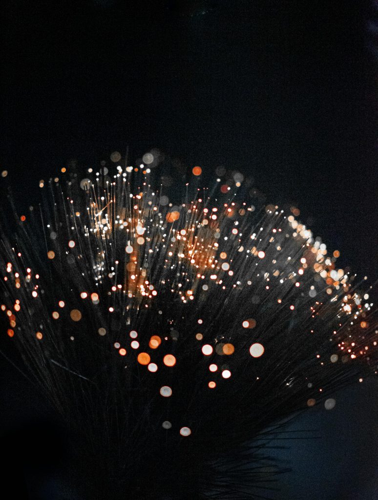 An artistic shot of fiber optic lights on a dark background creating a bokeh effect with vivid colors.